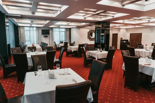 uma sala de jantar com mesas e cadeiras brancas em Hotel EMD em Bacau