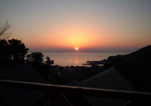 einen Sonnenuntergang über dem Meer mit der Sonne am Himmel in der Unterkunft GuestHouse StrawberryFarm Shirasaki-Ⅱ / Vacation STAY19358 in Ōbiki