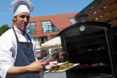 a man holding a plate of food on a grill at Grand Rose SPA Hotel in Kuressaare