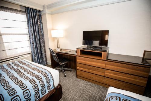 a hotel room with a bed and a desk and a television at The Belvedere Hotel in New York