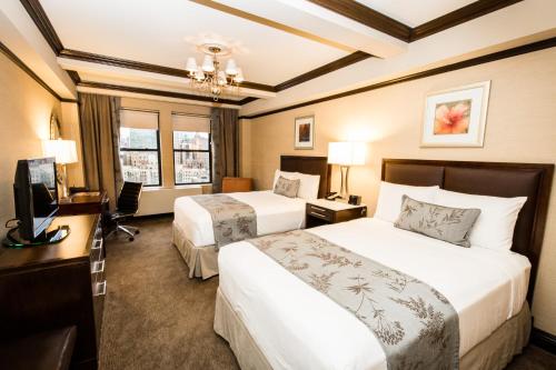 Cette chambre comprend deux lits, un bureau et une télévision. dans l'établissement The Belvedere Hotel, à New York