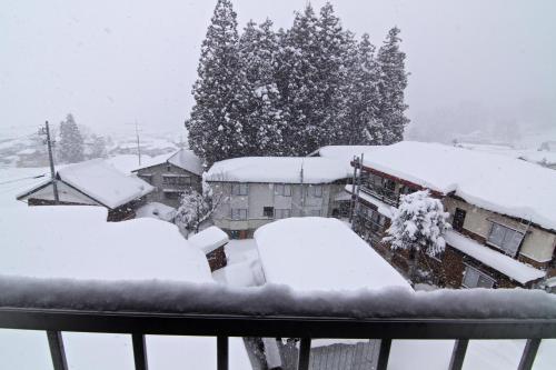a snow covered city with houses and a tree at Schanze Nozawa in Nozawa Onsen