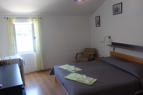 a bedroom with a bed and a chair and a window at Sobe MaMaLu in Valun