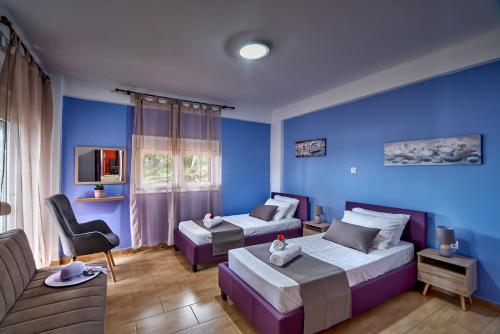 a blue room with two beds and a couch at Villa Aelia in Georgioupolis