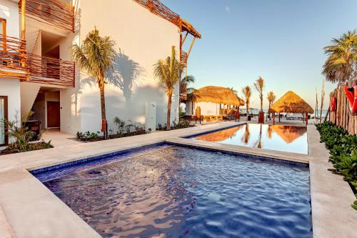 a swimming pool in front of a house with palm trees at Mystique Holbox by Royalton, A Tribute Portfolio Resort in Holbox Island