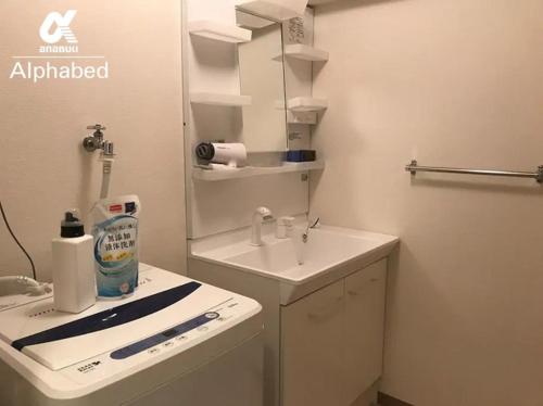 La salle de bains blanche est pourvue d'un lavabo et d'un miroir. dans l'établissement Alphabed Takamatsukouzaiekimae 102 / Vacation STAY 20340, à Takamatsu