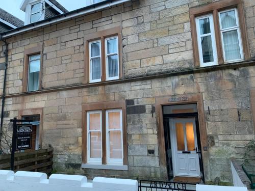 a stone building with a white door and windows at Ardvaich House in Oban