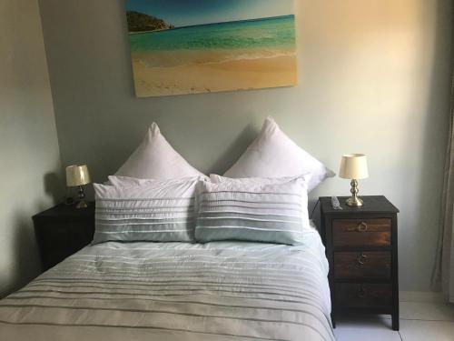 a bed with white pillows and a painting on the wall at Lala’s guest house in Johannesburg