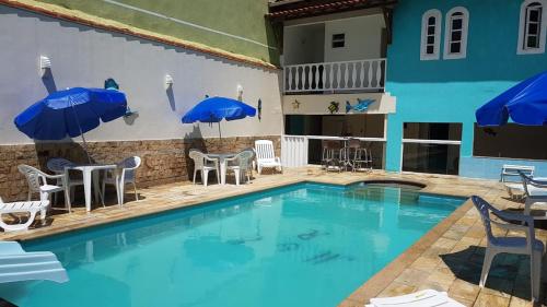 a large swimming pool with chairs and umbrellas at Suítes Xodo Tour in Arraial do Cabo