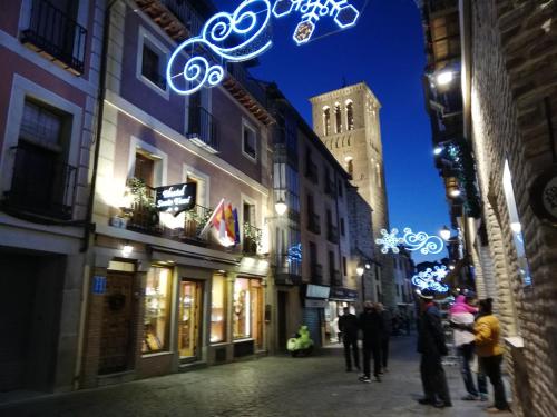 a group of people walking down a street at night at Hostal Santo Tomé in Toledo