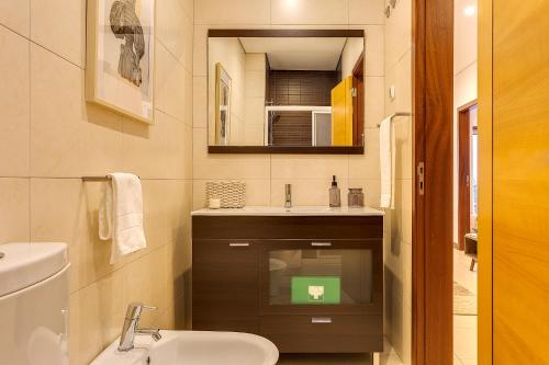 a bathroom with a sink and a toilet and a mirror at DA'HOME - Marquês Unique Terraza in Porto