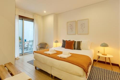 a bedroom with a large bed and a balcony at DA'HOME - Marquês Unique Terraza in Porto