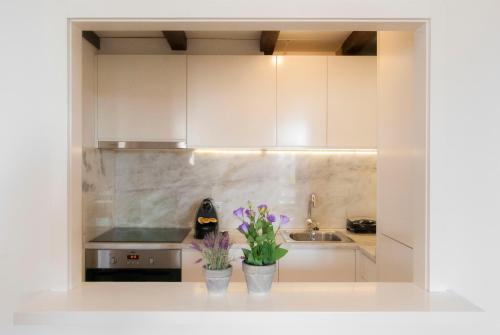 eine Küche mit weißen Schränken und lila Blumen auf der Theke in der Unterkunft DA'HOME - Vitoria Duplex Apartment in Porto