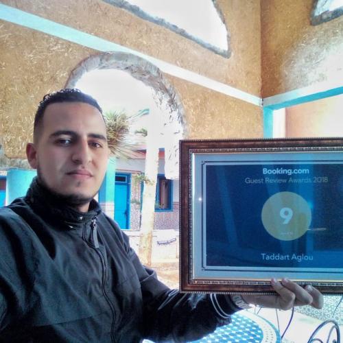 a man is holding a television in a room at Taddart Aglou in Zaouit Aglou