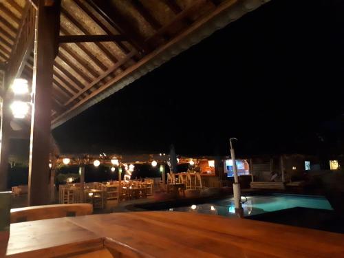 a swimming pool at night with a table and chairs at Sandy Beach Bungalows in Gili Islands