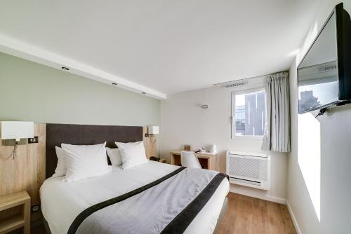 a bedroom with a large bed and a tv at Hôtel l'Amandier in Nanterre