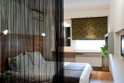 a bedroom with a bed and a window with a curtain at Capsis Hotel Thessaloniki in Thessaloniki