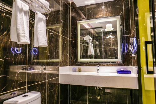 a black tiled bathroom with a sink and a mirror at Chao Man Hotel(Guangzhou Pazhou Exhibition Center Chigang Subway Station) in Guangzhou