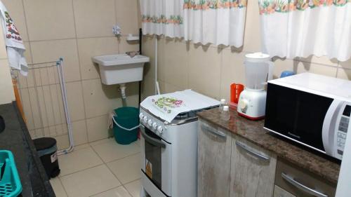 una pequeña cocina con microondas y fregadero en Apartamento lindo e completo, de frente para o mar, en Maragogi