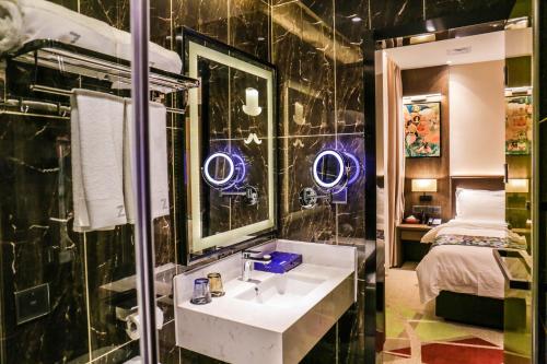 a bathroom with a sink and a mirror and a bed at Chao Man Hotel(Guangzhou Pazhou Exhibition Center Chigang Subway Station) in Guangzhou