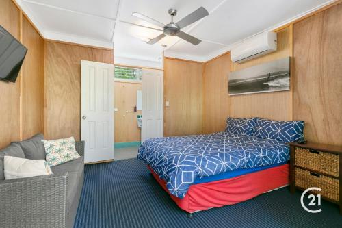 een slaapkamer met een bed en een bank bij Dolphins Backpackers in Sunshine Beach