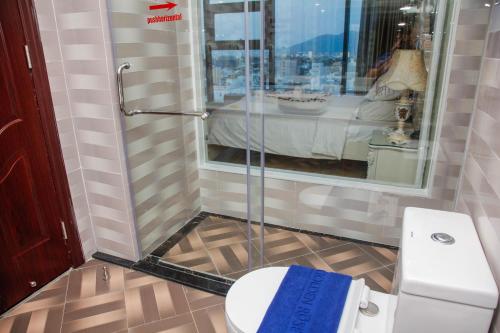 a bathroom with a toilet and a glass shower at Golden Rose Hotel in Da Nang