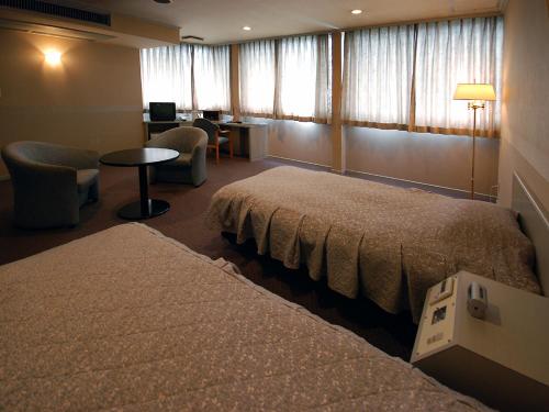 a hotel room with two beds and a table and chairs at Hotel Nagasaki in Nagasaki