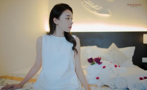 a woman in a white dress standing on a bed at Amamas Boutique Hotel Kuching in Kuching