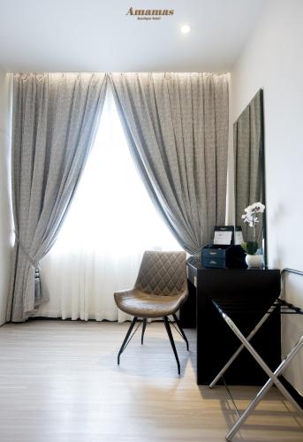 a room with a desk and a chair in front of a window at Amamas Boutique Hotel Kuching in Kuching