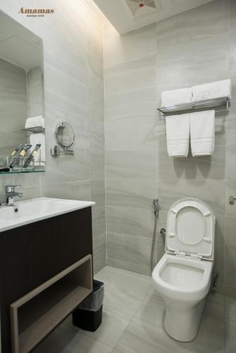 a bathroom with a white toilet and a sink at Amamas Boutique Hotel Kuching in Kuching