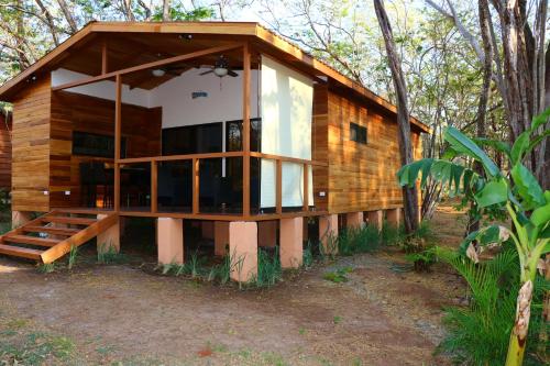 a wooden cabin with a porch in the woods at CASA NATURaL in Brasilito