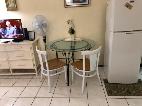 a glass table with chairs and a refrigerator in a kitchen at Beryls at Seawind on the Bay , Montego Bay , Jamaica in Montego Bay