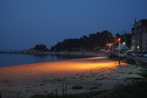 a beach at night with lights on the water at 양철지붕위의 고양이Cat on a Hot Tin Roof in Yangyang