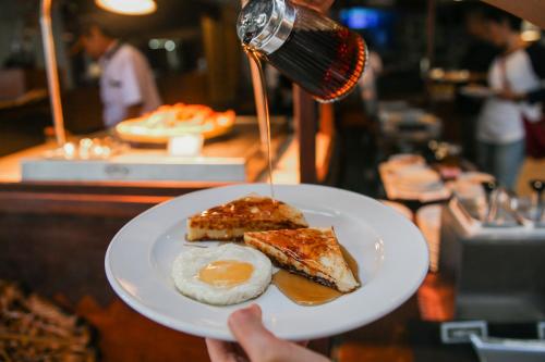 a person holding a plate of food with an egg and toast at Indra Maya Pool Villas in Lagoi