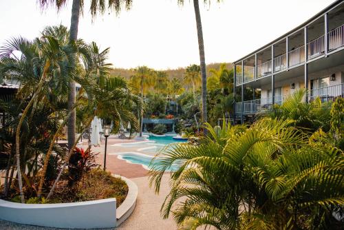 a resort with a pool and palm trees and a building at Mantra Club Croc in Airlie Beach