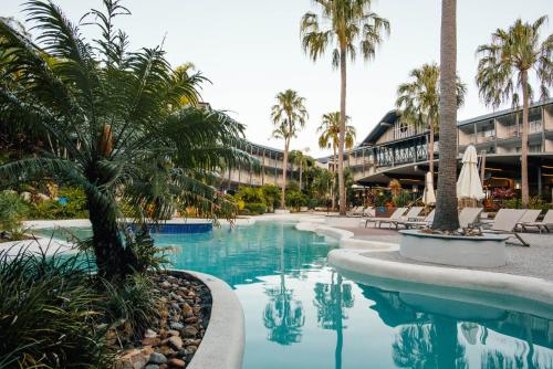 a swimming pool at a resort with palm trees at Mantra Club Croc in Airlie Beach