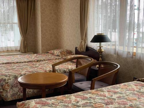 a hotel room with two beds and a table and chairs at Naeba Springs Hotel in Yuzawa