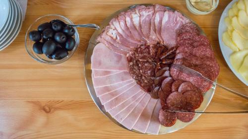 Un plato de carne y aceitunas en una mesa. en Noblesse Boutique Resort, en Sibiu