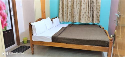 a bedroom with a bed with white pillows and a window at Jayaram Residency Tirupathi in Tirupati