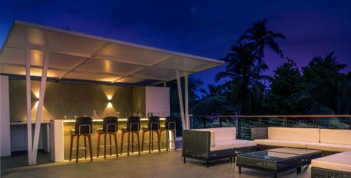 um pátio com cadeiras e um bar numa casa em StayVista Ashore 6BHK Infinity Pool Ocean View- Morjim em Morjim