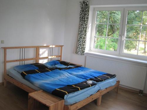 een slaapkamer met een bed met een blauw dekbed en 2 ramen bij Wohnung im Park in Thulendorf