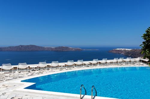 a swimming pool with lounge chairs and the ocean at Xenones Filotera in Imerovigli