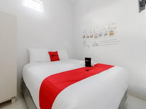 ein weißes Bett mit einer roten Decke darüber in der Unterkunft RedDoorz Plus near Taman Rasuna Menteng in Jakarta