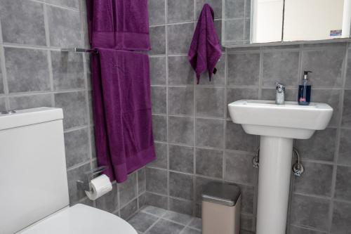 a bathroom with a toilet and a sink and purple towels at Stunning Views To Beat Lockdown Blues in Sydney