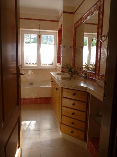 a bathroom with a tub and a sink and a mirror at Casal das Oliveiras in Setúbal