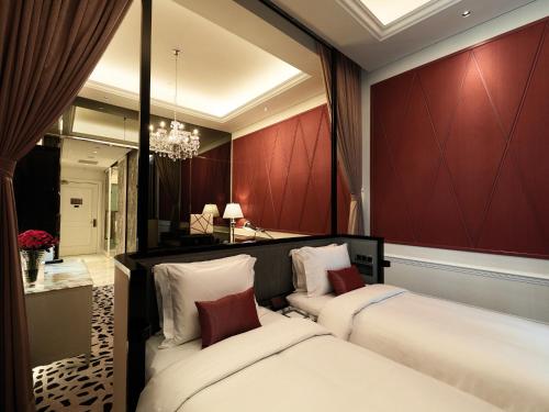 two beds in a room with red walls and a mirror at Resorts World Genting - Crockfords in Genting Highlands