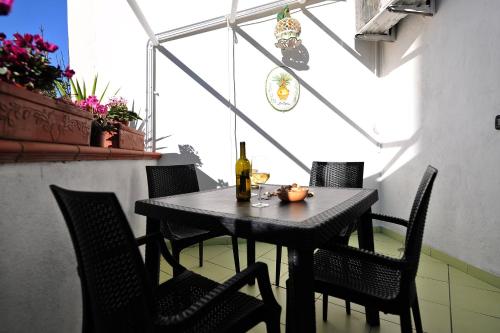 a black table with chairs and a bottle of wine at B&b Le Cycas in Castellammare di Stabia