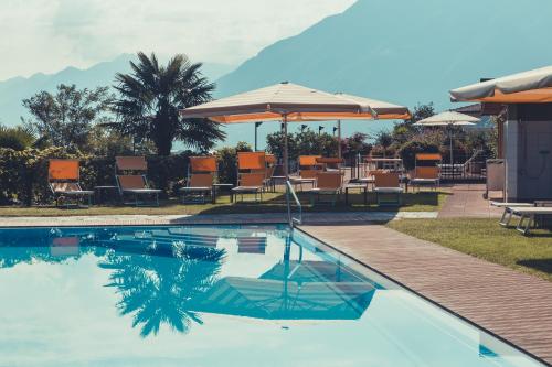 a swimming pool with chairs and umbrellas in a resort at B&B Toblerina in Ascona