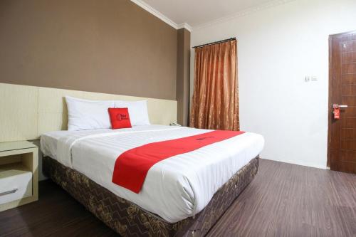 Cette chambre comprend un grand lit avec une couverture rouge. dans l'établissement RedDoorz near Stadion Manahan Solo, à Solo