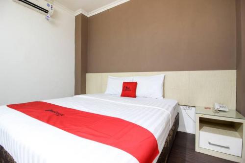 a bedroom with a bed with a red blanket on it at RedDoorz near Stadion Manahan Solo in Solo